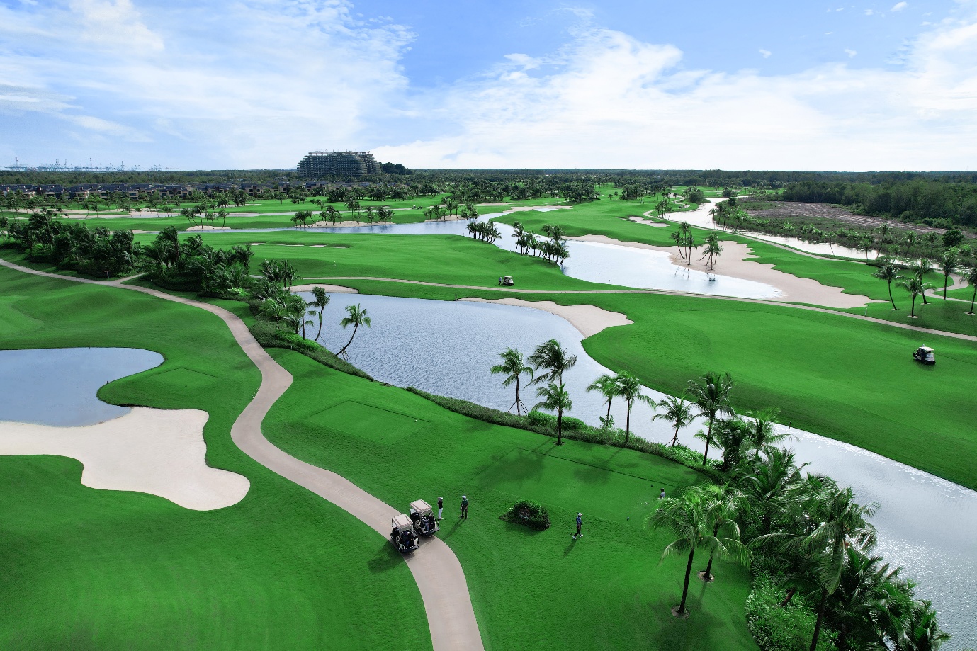 Panoramic view of Forest City Golf Resort with lush greenery, white bunkers, sunlit lakes, and the luxury hotel towers.